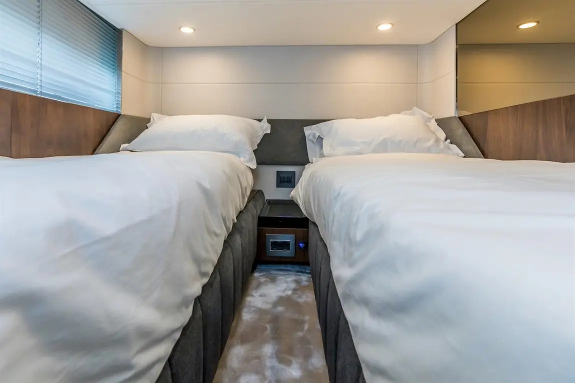 Two neatly made single beds with white bedding, situated in a modern, well-lit room with wood accents.